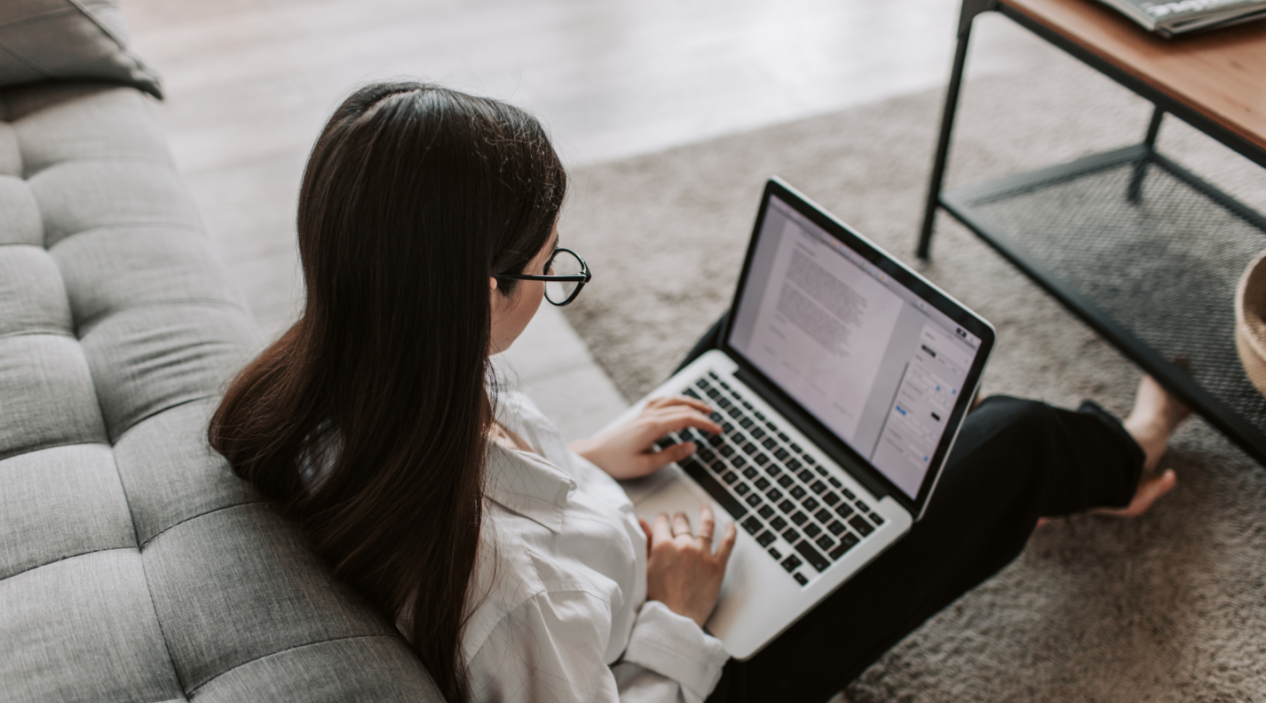 female working on a laptop while sitting on the floor