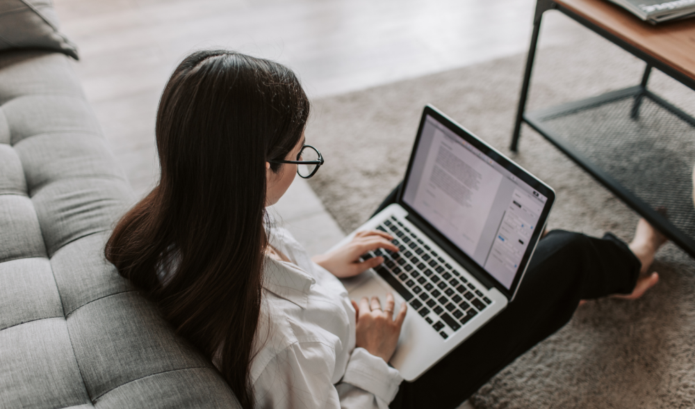 female working on a laptop while sitting on the floor