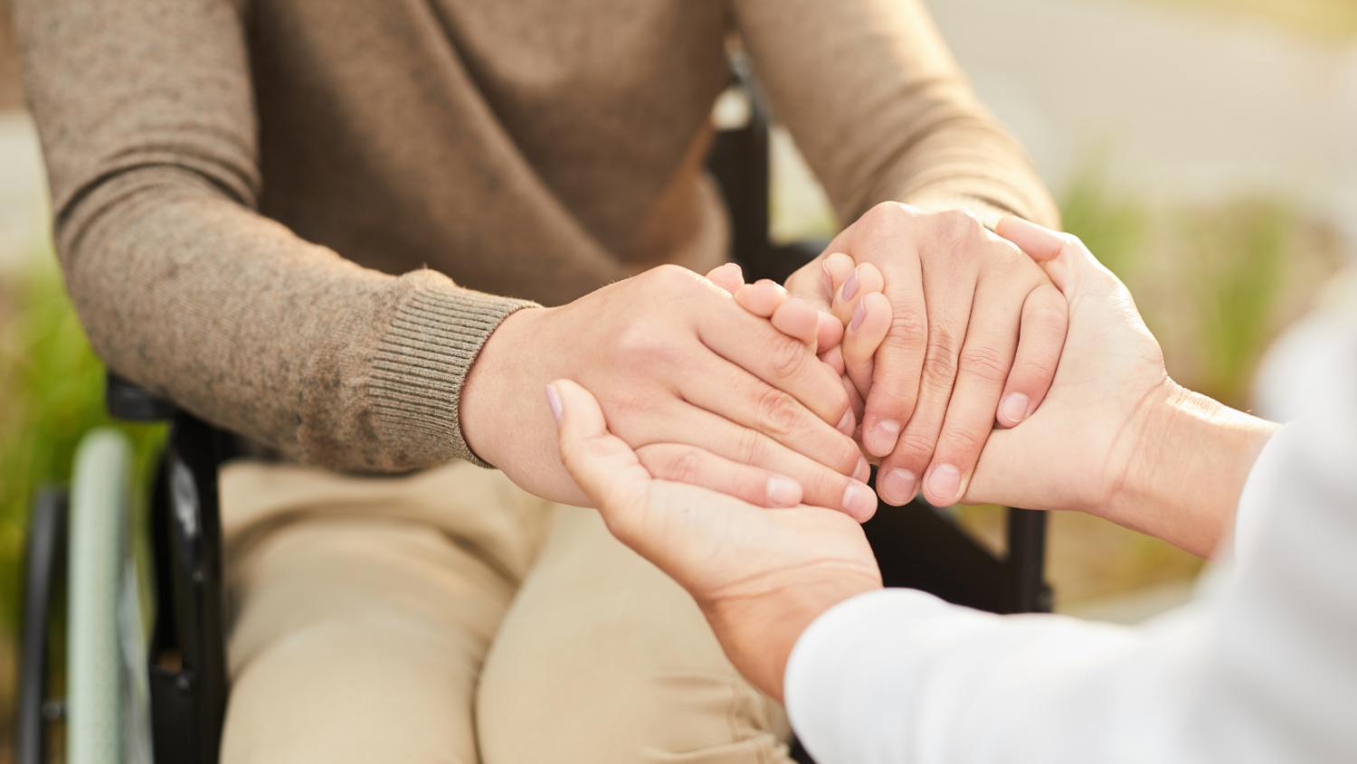 a person in a wheelchair clasping hands with another person